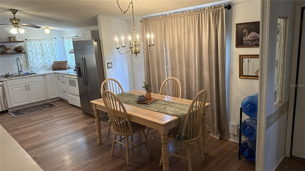 A dining area with a wooden table and chairs sits adjacent to a white kitchen — 6344 BASS HIGHWAY, ST CLOUD, FL