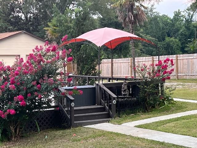 A backyard deck features a hot tub, a red canopy, and surrounding crape myrtle bushes — 1347 WISHBONE ROAD, CANTONMENT, FL
