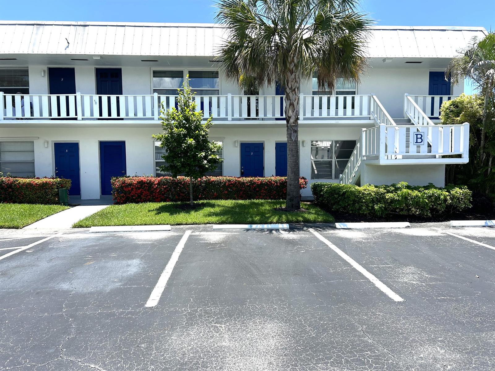 A two-story white apartment building features blue doors, a balcony, and a parking lot — 2929 SE Ocean Boulevard # 2, Stuart FL 34996, STUART, FL