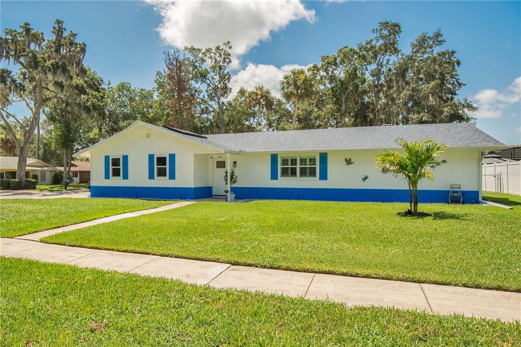 A single-story house with white siding, blue trim, and blue shutters sits on a lawn — 944 BENTWOOD LANE, PORT ORANGE, FL