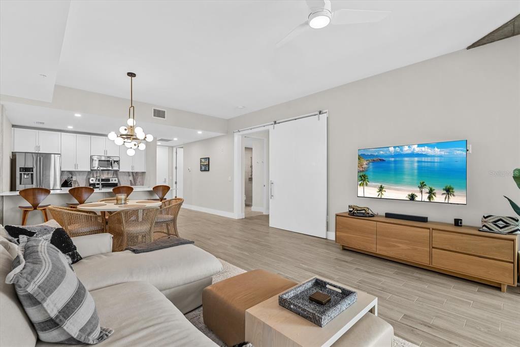 A modern open-concept living and dining area with light wood floors and white cabinetry — 332 COCOANUT AVENUE UNIT 302, SARASOTA, FL