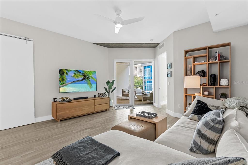 A living room with a sectional sofa, wooden media console, and an open-concept kitchen — 332 COCOANUT AVENUE UNIT 302, SARASOTA, FL
