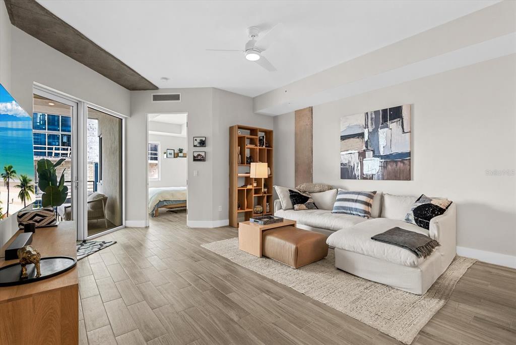 A modern living room features a sectional sofa, media console, shelving unit, and balcony access — 332 COCOANUT AVENUE UNIT 302, SARASOTA, FL
