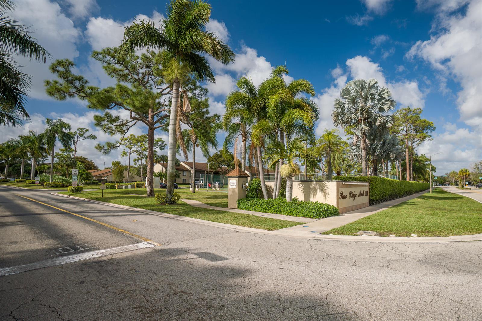 An exterior view of a Pine Ridge North III community entrance with palm trees — 707 Sunny Pine Way # C2, FL 33415, FL
