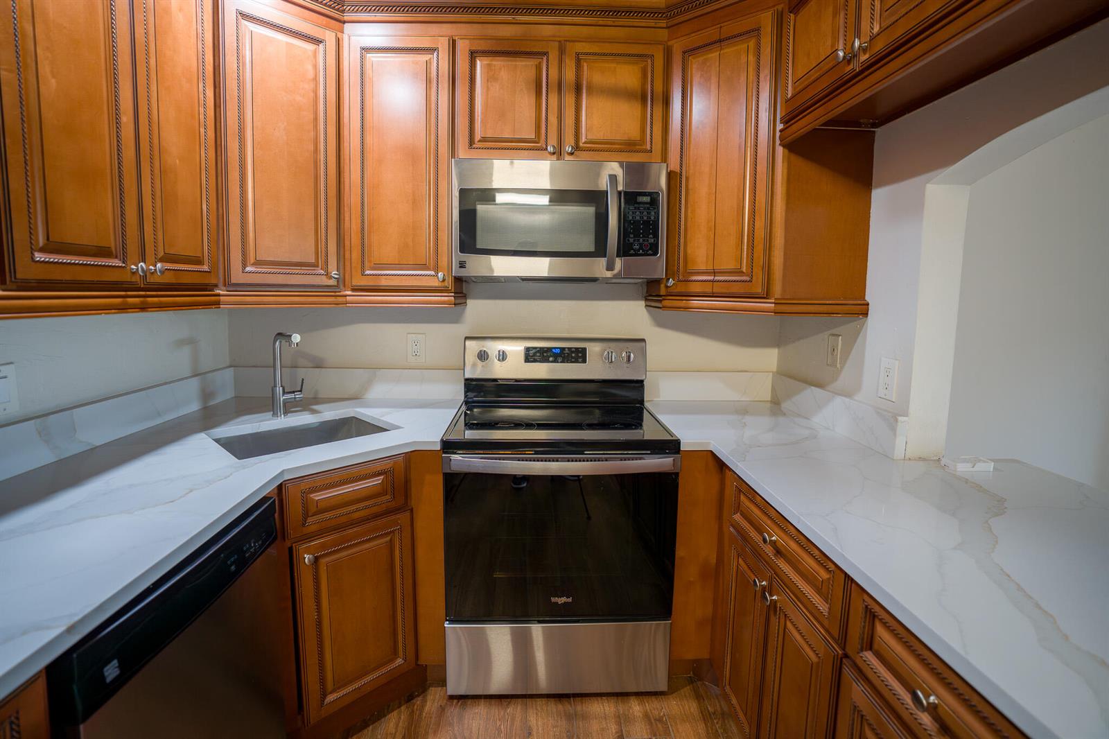 A kitchen features wood cabinets, stainless steel appliances, and white countertops with gray veining — 707 Sunny Pine Way # C2, FL 33415, FL