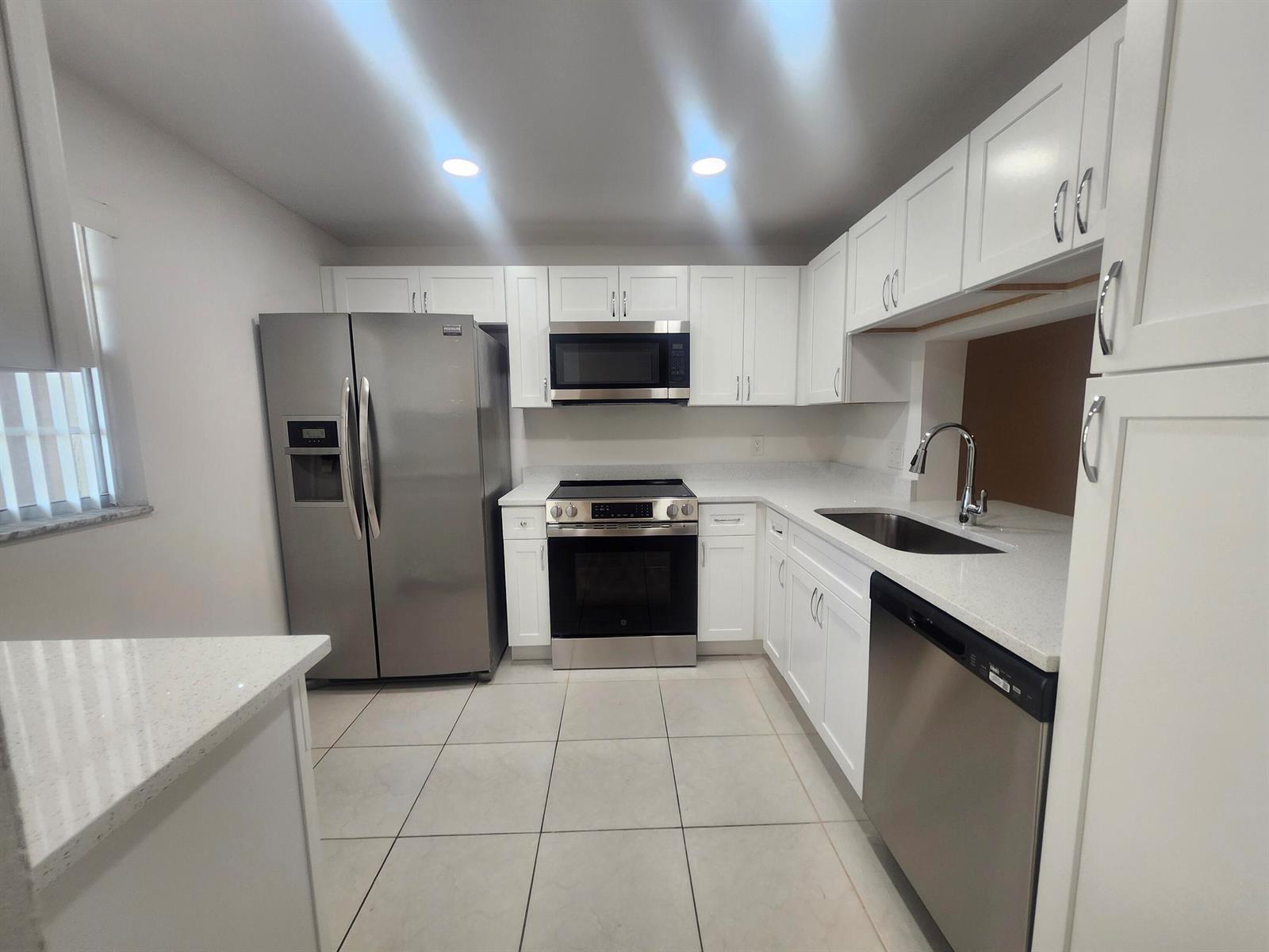 A kitchen features white cabinets, stainless steel appliances, and light-colored countertops — 330 NE 26th Avenue # 202, Boynton Beach FL 33435, BOYNTON BEACH, FL