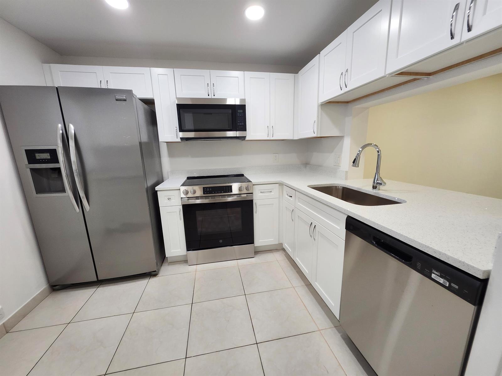 A kitchen features white cabinets, stainless steel appliances, and light-colored countertops — 330 NE 26th Avenue # 202, Boynton Beach FL 33435, BOYNTON BEACH, FL