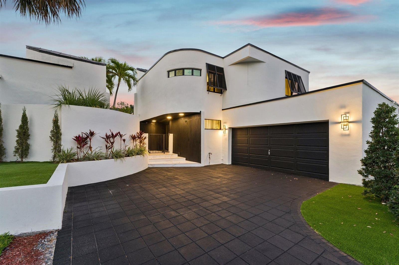 A modern two-story house features a curved white facade, black garage door, and paved driveway — 2651 NE 22nd Court, Pompano Beach FL 33062, POMPANO BEACH, FL