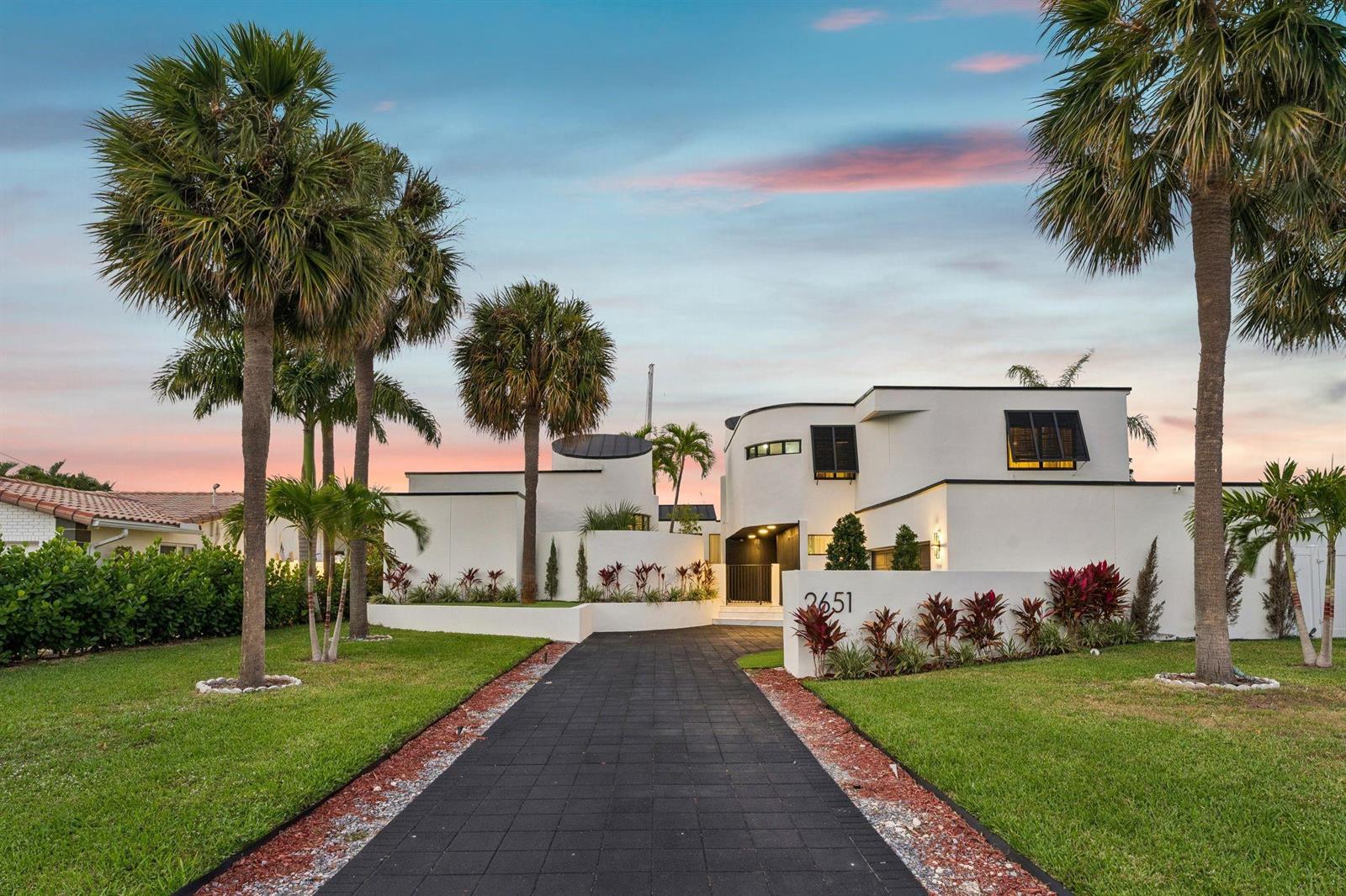 A modern white house with curved walls and a paved driveway sits among palm trees — 2651 NE 22nd Court, Pompano Beach FL 33062, POMPANO BEACH, FL