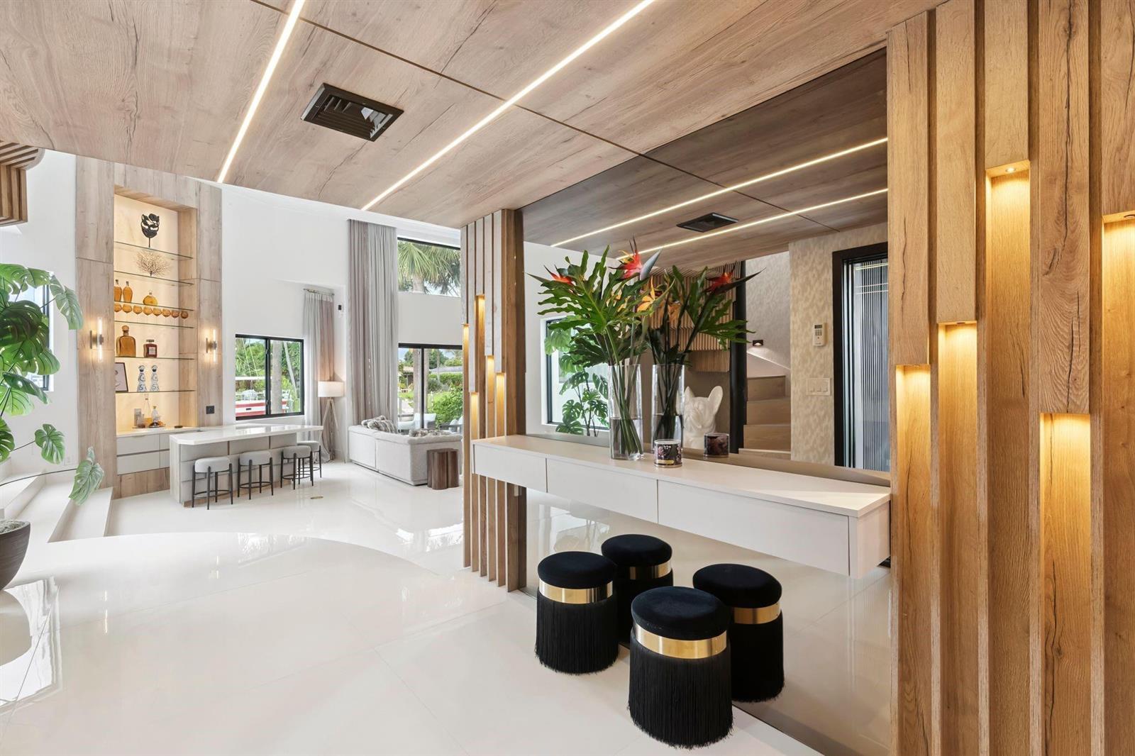 A modern living area features a white console table, black stools, and wood-paneled ceilings — 2651 NE 22nd Court, Pompano Beach FL 33062, POMPANO BEACH, FL