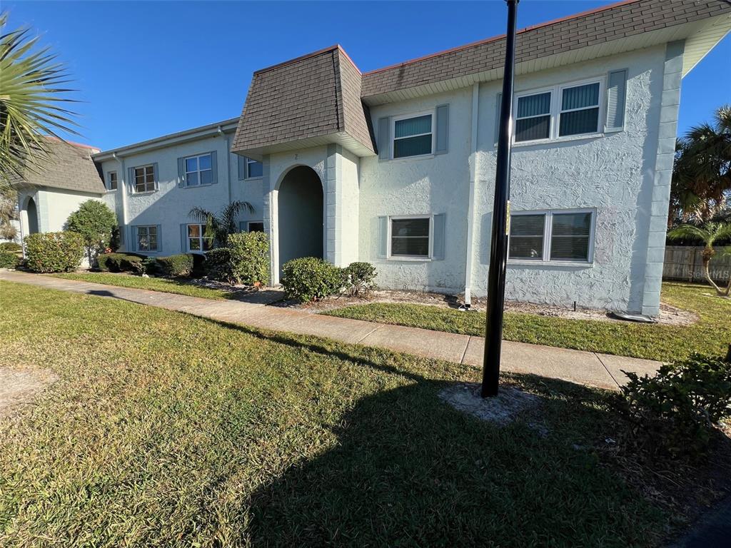 A two-story apartment building with light-colored stucco walls and a brown shingled roof — 387 S MCMULLEN BOOTH ROAD UNIT 13, CLEARWATER, FL