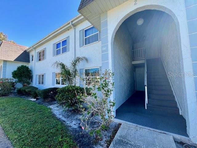 The exterior of a multi-story residential building features a covered stairwell entrance and landscaping — 387 S MCMULLEN BOOTH ROAD UNIT 13, CLEARWATER, FL