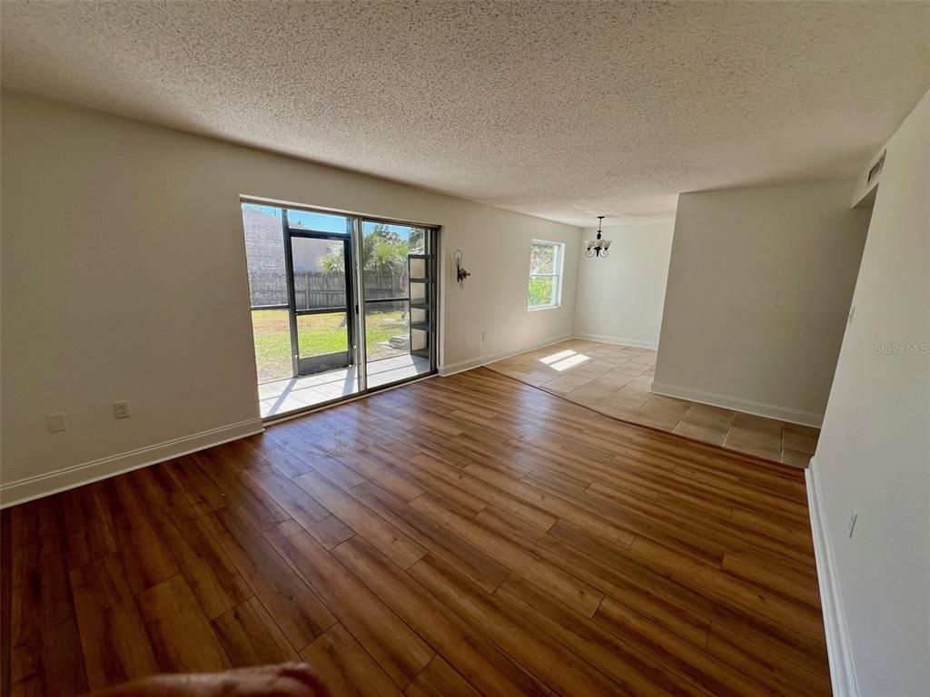 A living room with wood-look flooring, sliding glass doors, and an adjacent tiled dining area — 387 S MCMULLEN BOOTH ROAD UNIT 13, CLEARWATER, FL