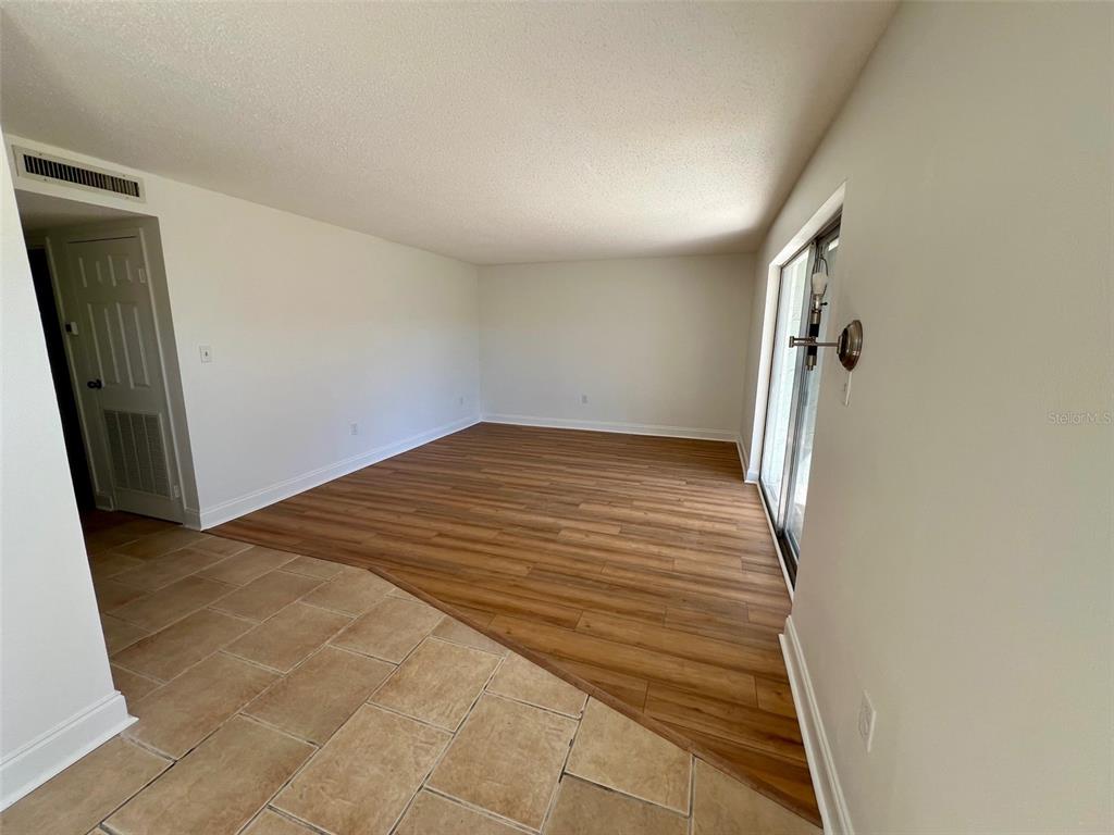 An interior view showing a living area with wood-look flooring and a tiled entryway — 387 S MCMULLEN BOOTH ROAD UNIT 13, CLEARWATER, FL