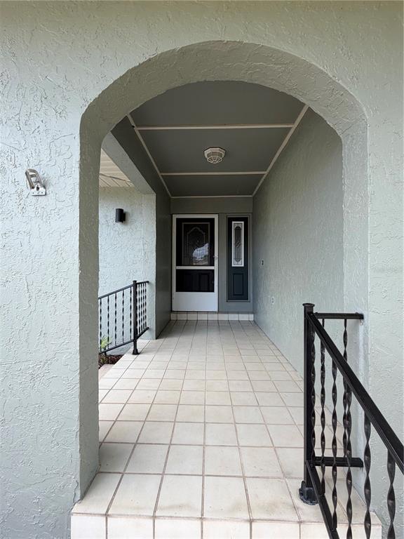 A covered entryway features a tiled floor, an arched opening, and black metal railings — 1454 GRAND CAYMAN CIRCLE, WINTER HAVEN, FL
