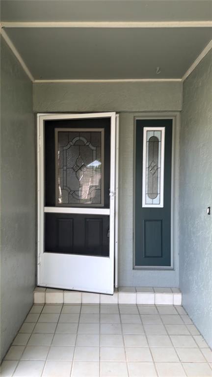A front entryway features a white storm door, a side light, and light-colored floor tiles — 1454 GRAND CAYMAN CIRCLE, WINTER HAVEN, FL
