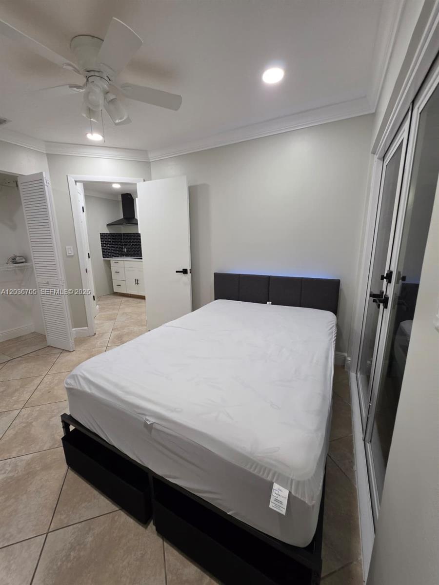 A bedroom with tile flooring, a bed, a ceiling fan, and an adjacent kitchen — MIAMI, FL