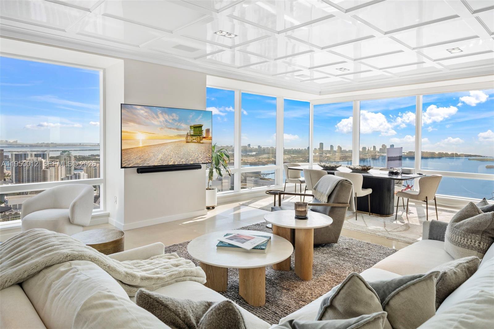 A modern living and dining area features floor-to-ceiling windows, a coffered ceiling, and panoramic views — 1425 Brickell Ave # 58E, Miami FL 33131, MIAMI, FL