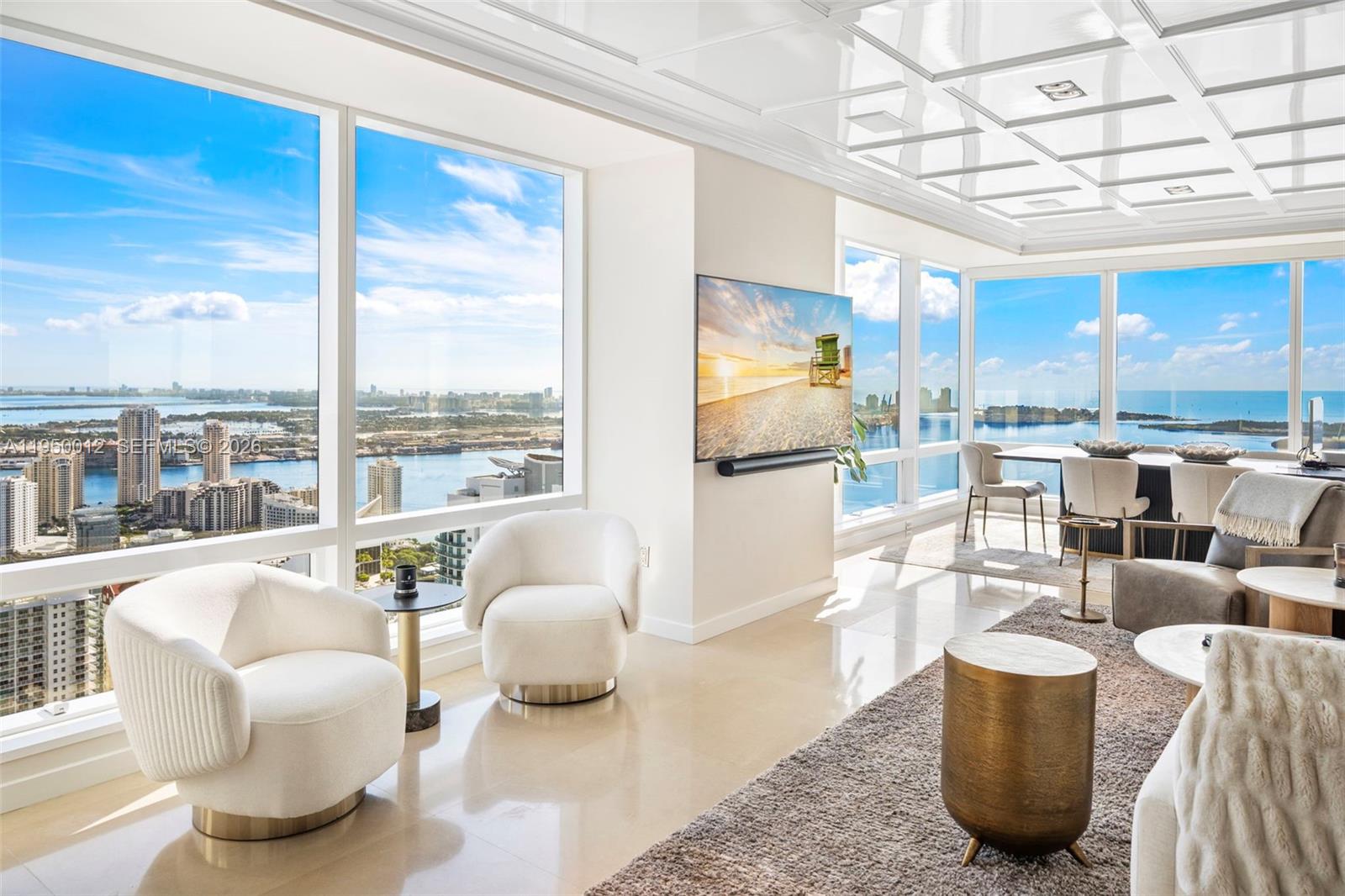 A modern living room features floor-to-ceiling windows with water views and a coffered ceiling — 1425 Brickell Ave # 58E, Miami FL 33131, MIAMI, FL