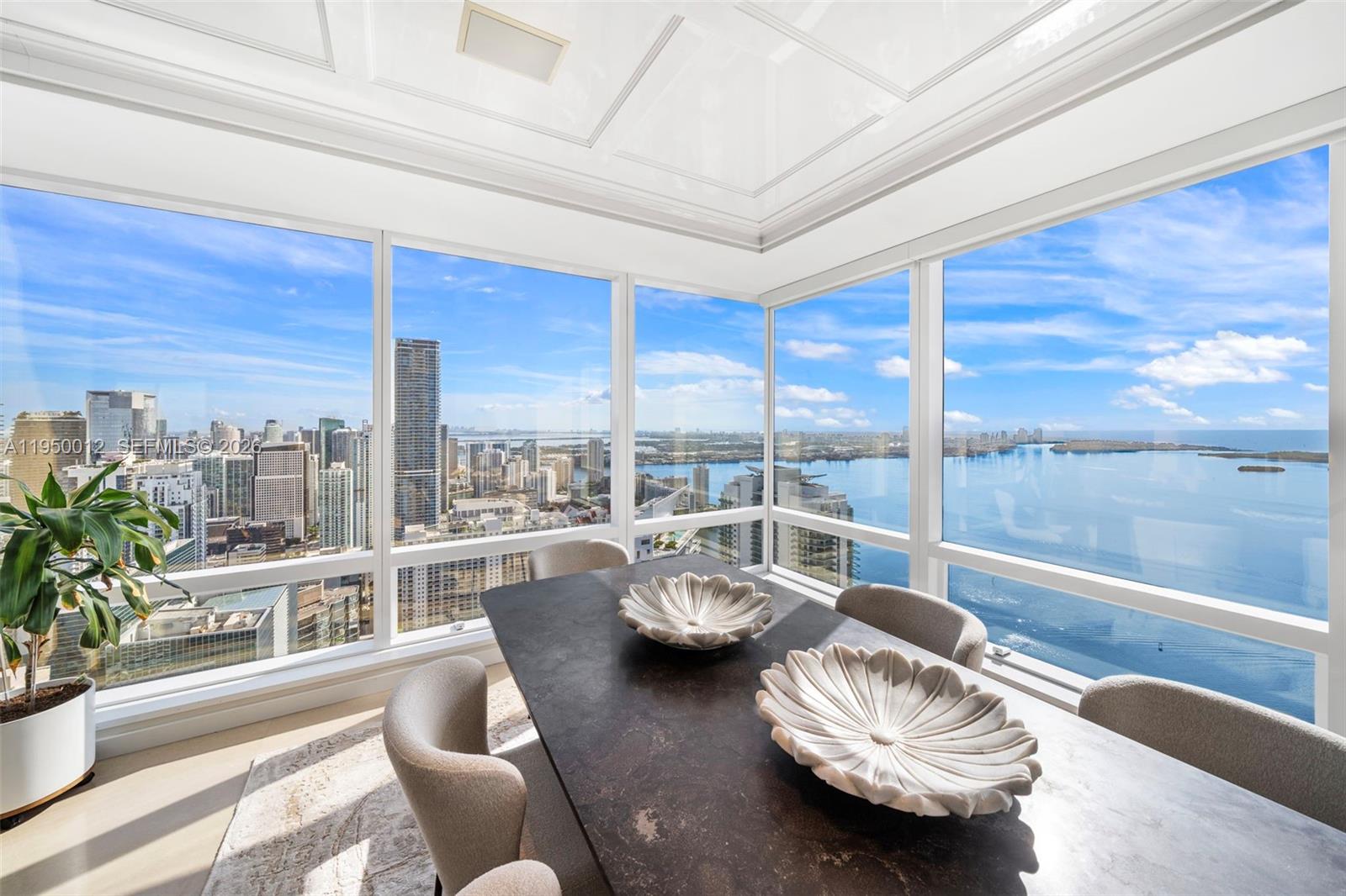A dining room features a dark table, modern chairs, and floor-to-ceiling windows with city views — 1425 Brickell Ave # 58E, Miami FL 33131, MIAMI, FL