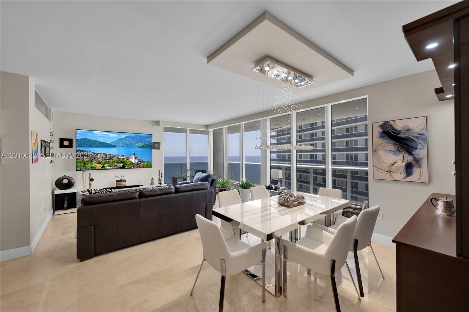 A modern living and dining area features a large television, ocean views, and contemporary furniture — 1800 S Ocean Dr # 2205, Hallandale Beach FL 33009, HALLANDALE BEACH, FL
