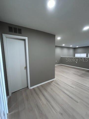 A room with light wood-look flooring, gray walls, recessed lighting, and a closed white door — 4010 DOLOMITE STREET UNIT A6, ORLANDO, FL