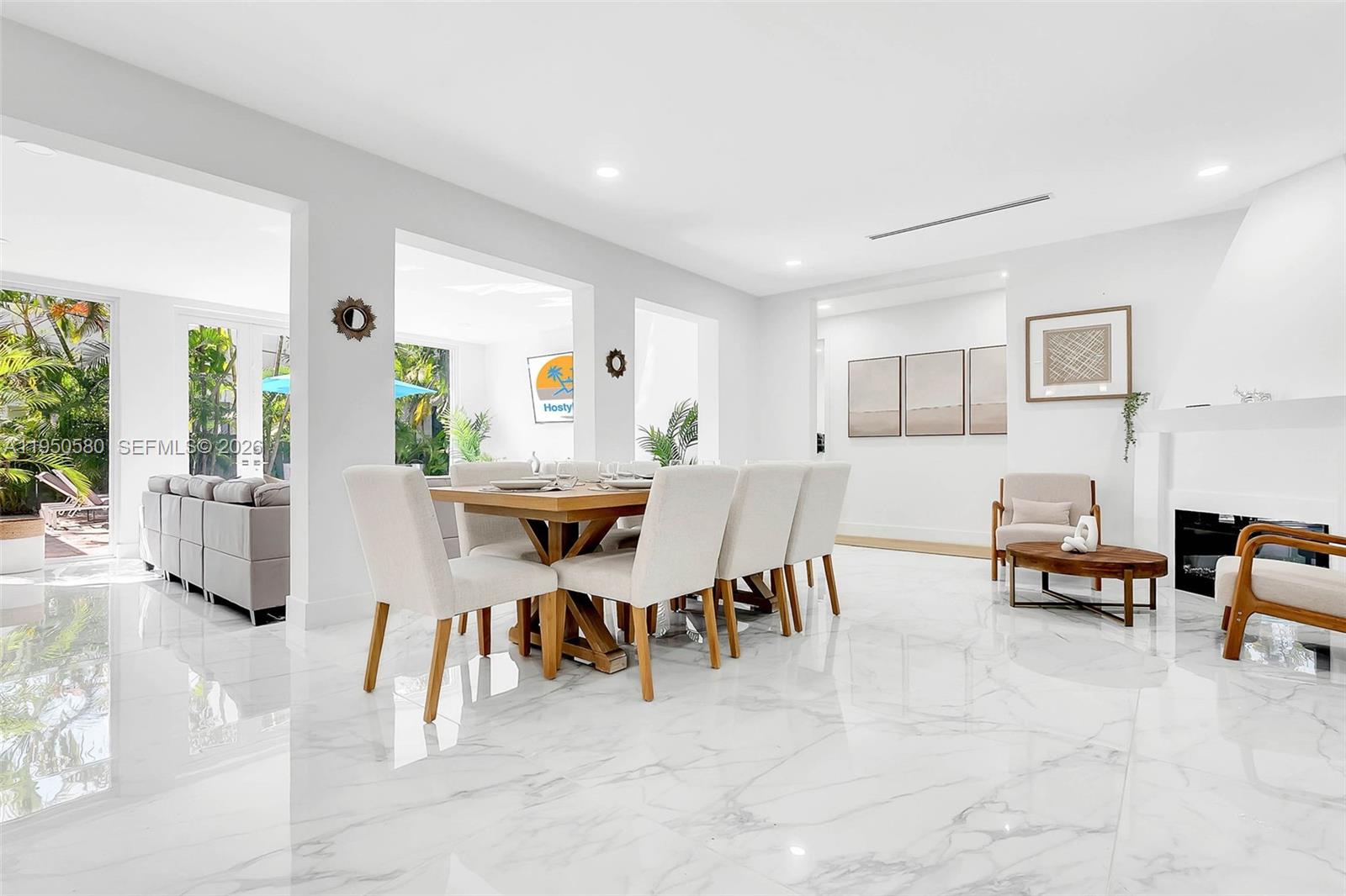 A bright dining room features a wooden table, upholstered chairs, and white marble flooring — 1702 Espanola Dr, Miami FL 33133, MIAMI, FL