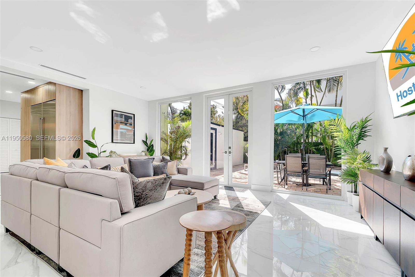 A bright living room features a large sectional sofa, marble floors, and glass doors to a patio — 1702 Espanola Dr, Miami FL 33133, MIAMI, FL
