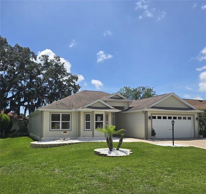A single-story house with light siding, a two-car garage, and a landscaped front yard — 1417 VALPARAISO STREET, THE VILLAGES, FL