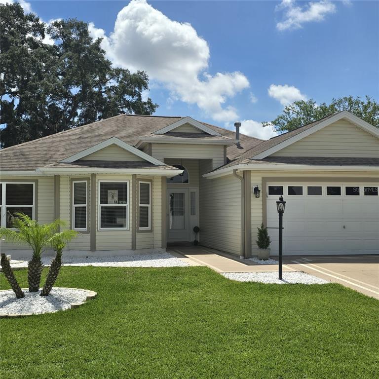 A single-story house with beige siding, a two-car garage, and a front lawn — 1417 VALPARAISO STREET, THE VILLAGES, FL
