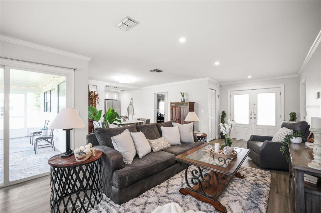 A living room features a gray sofa, a coffee table, and a view of a patio — 10559 41ST COURT N, CLEARWATER, FL
