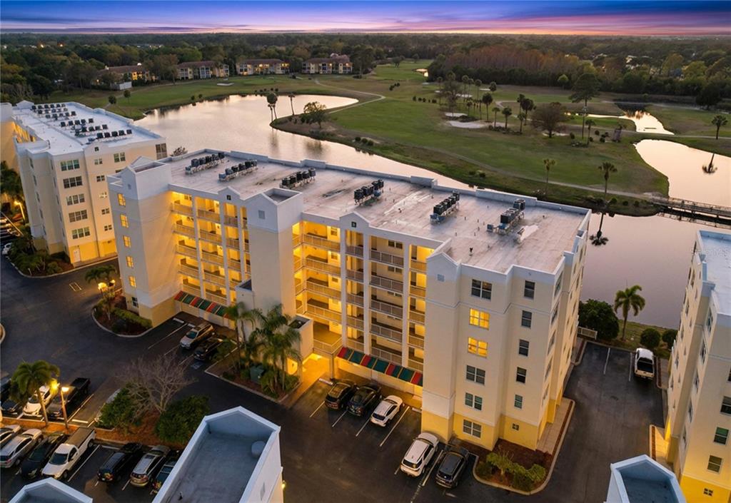 An aerial view shows a multi-story apartment building with a parking lot and golf course — 1200 COUNTRY CLUB DR UNIT 5404, LARGO, FL