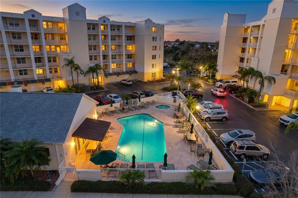 An aerial view of a swimming pool area surrounded by multi-story apartment buildings and parking — 1200 COUNTRY CLUB DR UNIT 5404, LARGO, FL