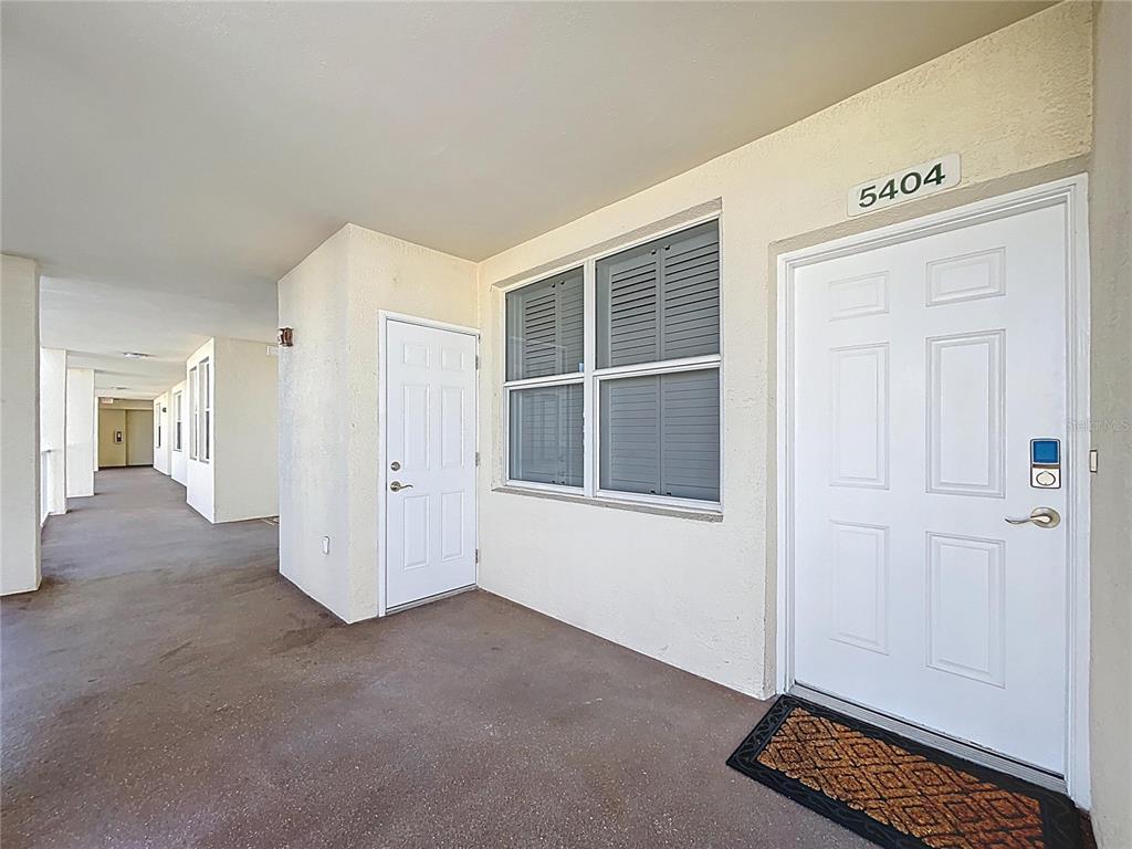 A covered exterior walkway leads to a white front door labeled 5404 and a window — 1200 COUNTRY CLUB DR UNIT 5404, LARGO, FL