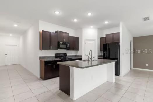 A kitchen features dark wood cabinets, a central island, and stainless steel appliances — 11207 SAGE CANYON DRIVE, RIVERVIEW, FL