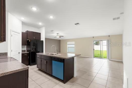 A kitchen with dark cabinets, a center island, and tile flooring opens to a living area — 11207 SAGE CANYON DRIVE, RIVERVIEW, FL