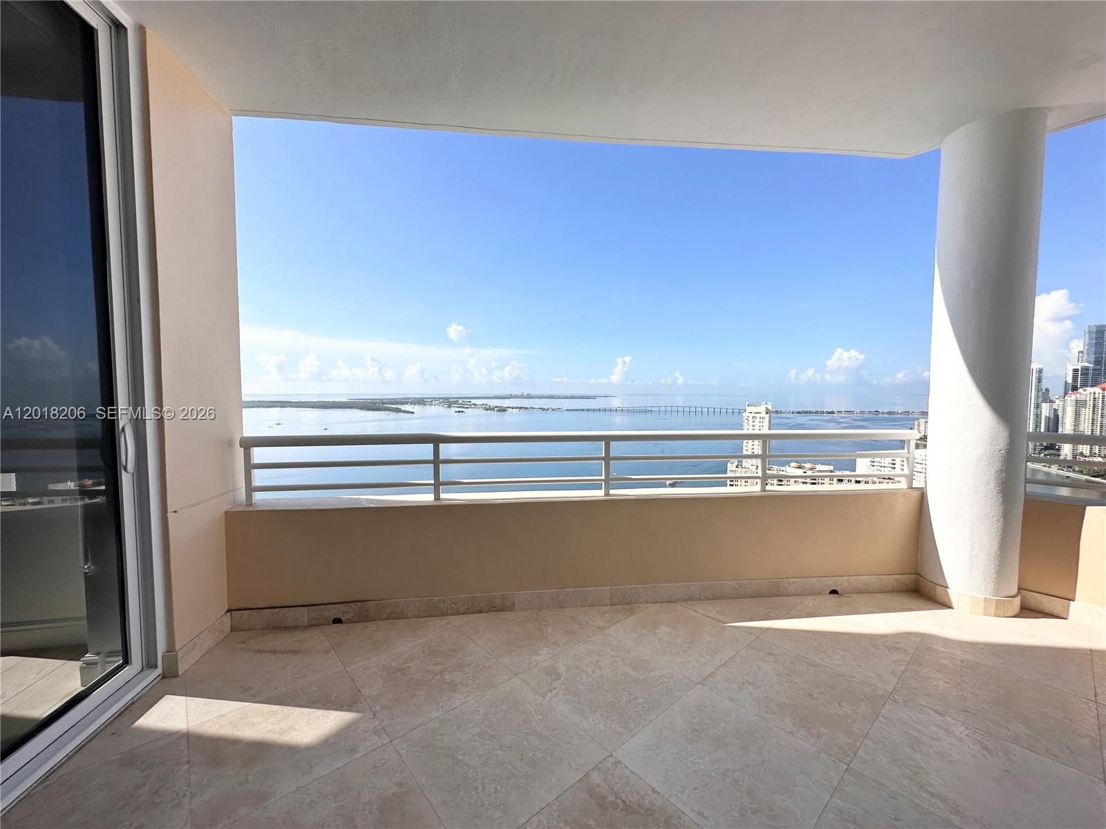 A balcony with tile flooring overlooks the ocean and a distant bridge — 808 Brickell Key Dr # 3608, Miami FL 33131, MIAMI, FL