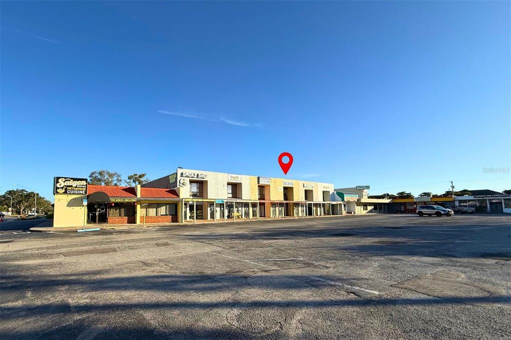 A strip mall with a large parking lot under a clear blue sky — 3627 WEBBER STREET, SARASOTA, FL