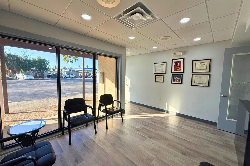 A waiting room with light wood-look flooring, black chairs, and framed wall art — 3627 WEBBER STREET, SARASOTA, FL