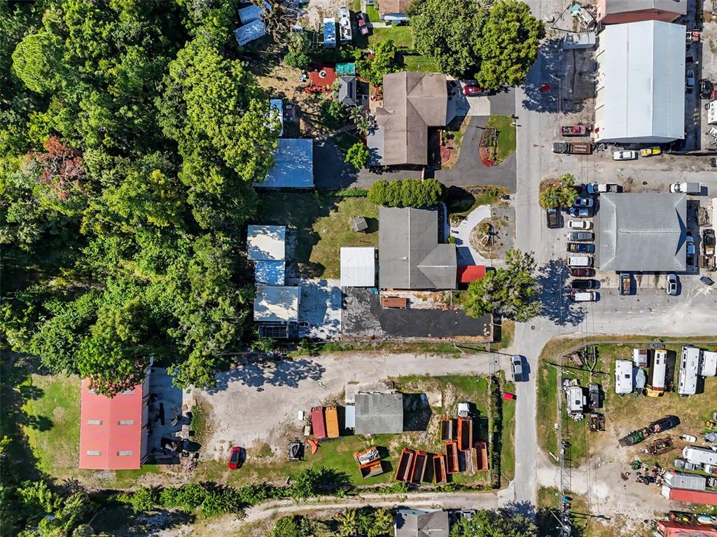 An aerial view shows a residential property with multiple outbuildings, trees, and adjacent commercial lots — 7813 LEO KIDD AVENUE, PORT RICHEY, FL