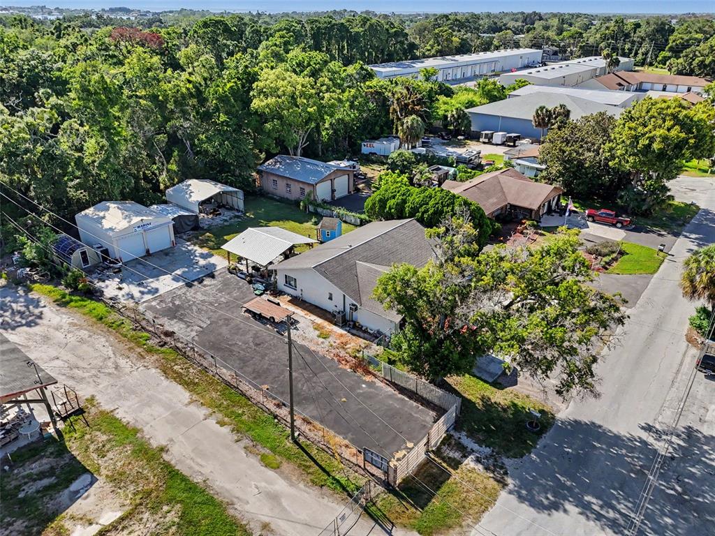 An aerial view shows a residential property with multiple outbuildings, a paved driveway, and trees — 7813 LEO KIDD AVENUE, PORT RICHEY, FL