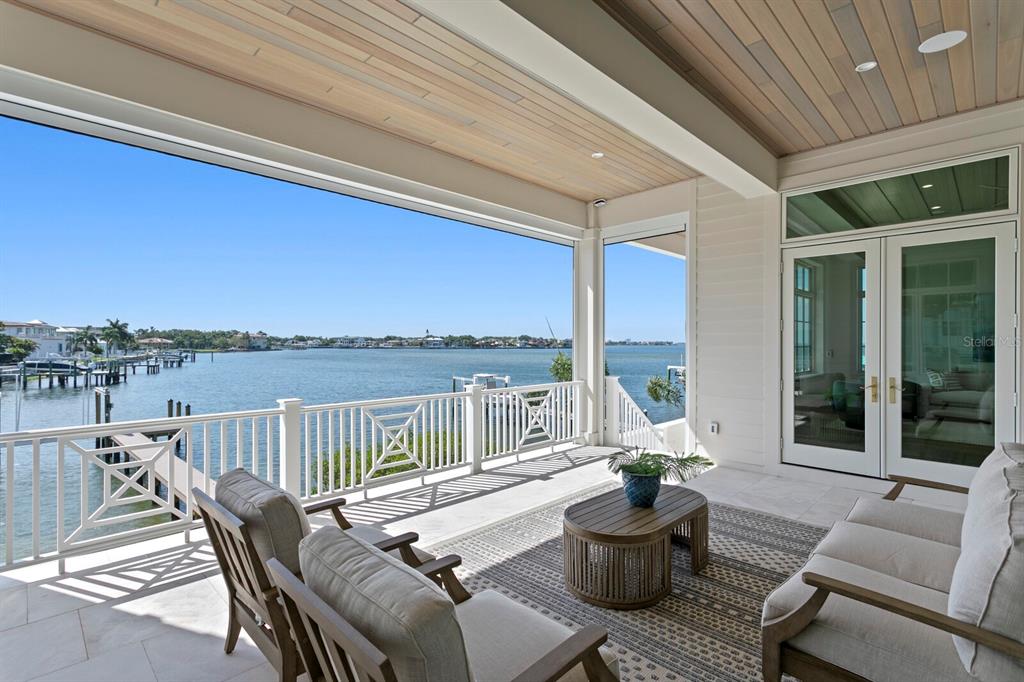 A covered outdoor patio features a wooden ceiling, white railings, and a view of water — 16 SANDPIPER ROAD, TAMPA, FL