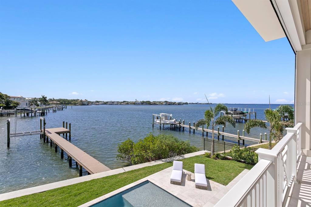 A balcony overlooks a swimming pool, a grassy lawn, a private dock, and the bay — 16 SANDPIPER ROAD, TAMPA, FL