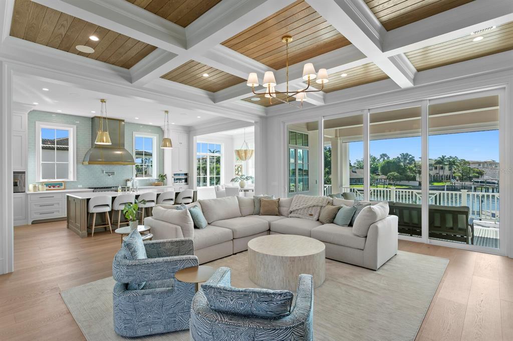A bright open-concept living room features a coffered wood ceiling, large sliding doors, and kitchen — 16 SANDPIPER ROAD, TAMPA, FL