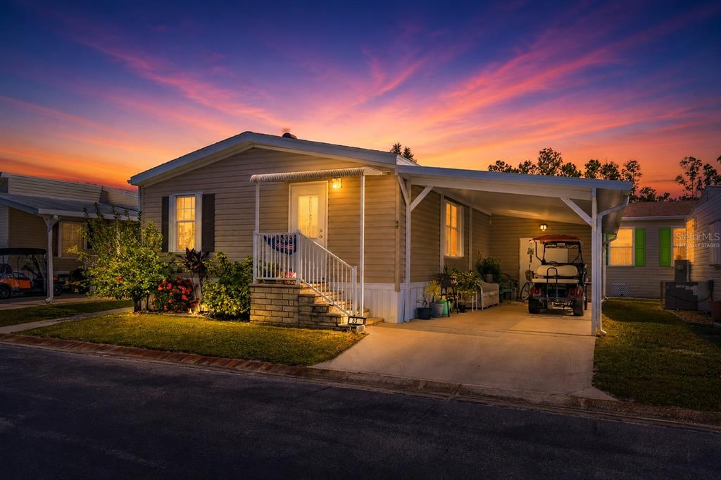 A single-story mobile home with a carport and front steps at sunset — 1000 KINGS HIGHWAY UNIT 54, PUNTA GORDA, FL