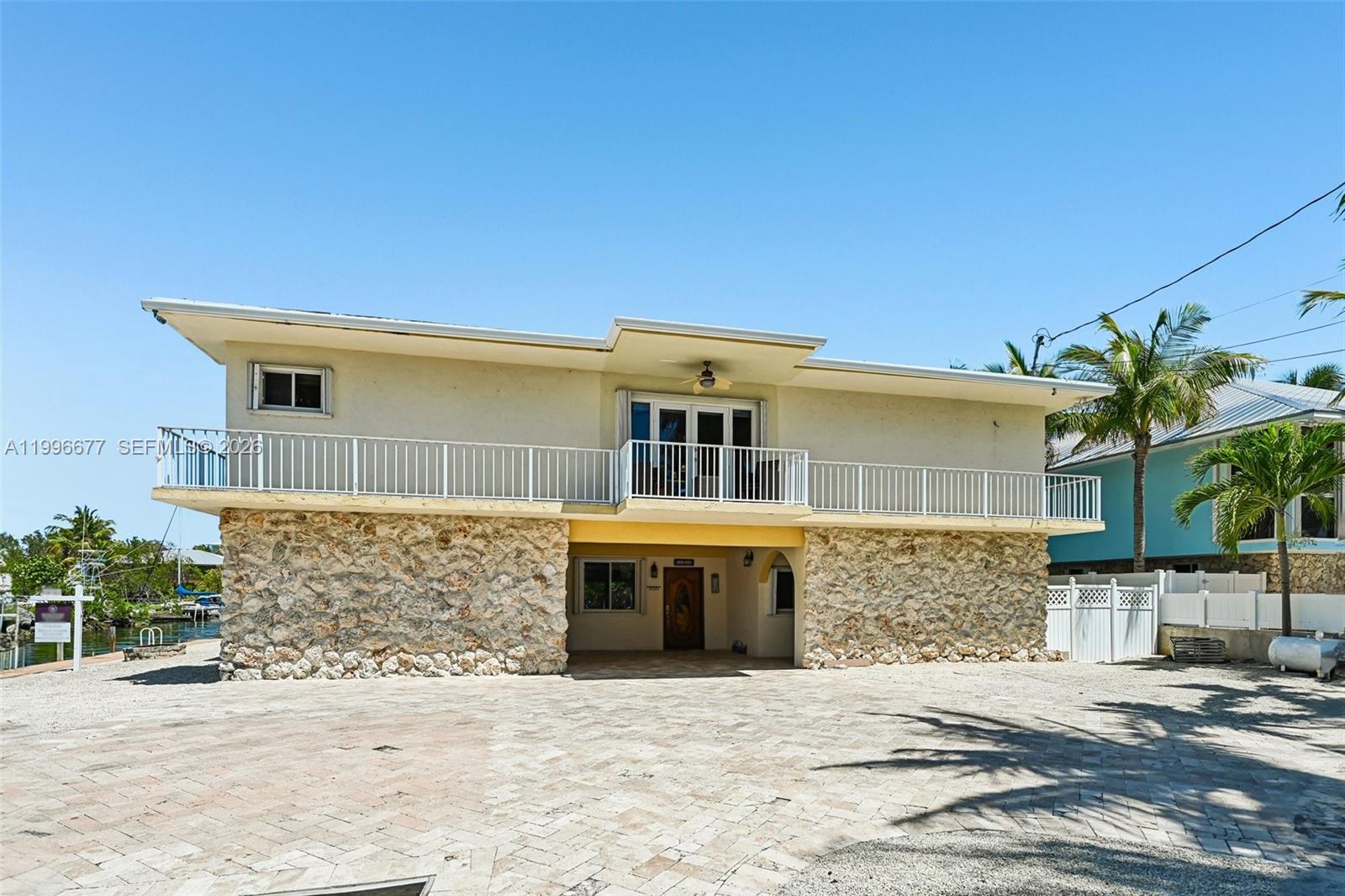 A two-story house features a stone-clad ground floor and a balcony on the upper level — 201 Wildwood Cir, Key Largo FL 33037, KEY LARGO, FL