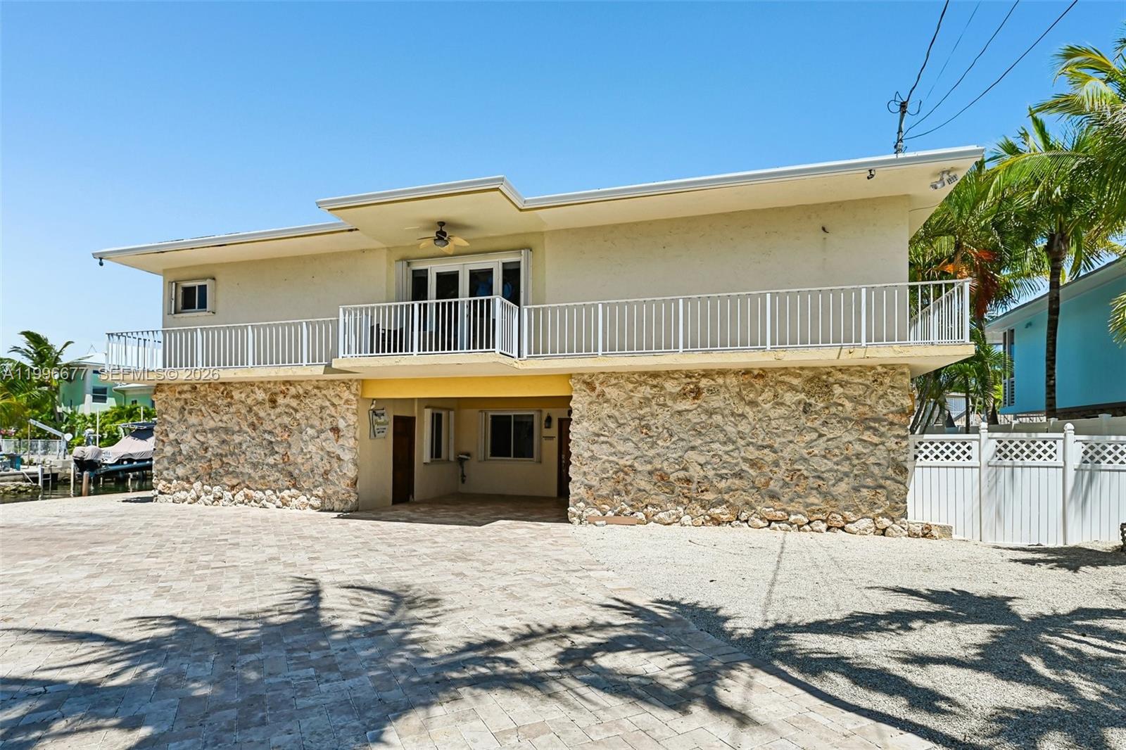 A two-story house features a stone-clad ground level and a balcony on the upper floor — 201 Wildwood Cir, Key Largo FL 33037, KEY LARGO, FL