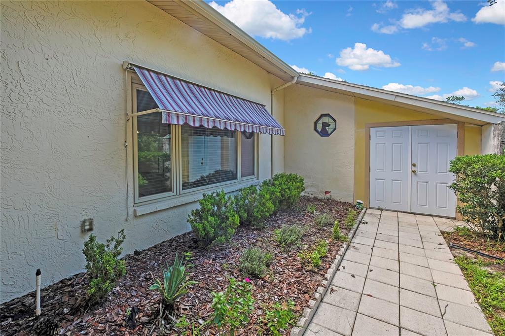 A house exterior features a striped window awning, a tiled walkway, and double entry doors — 12 MAYFLOWER COURT E, HOMOSASSA, FL