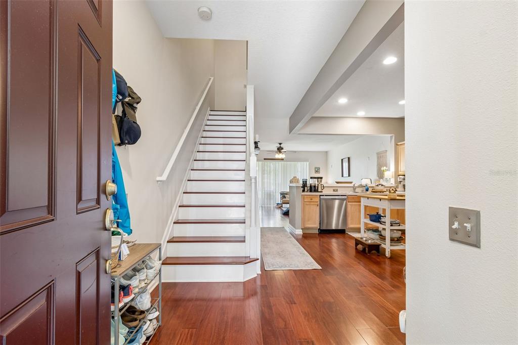 An entryway with a staircase leads into a kitchen with hardwood floors and stainless appliances — 26606 CASTLEVIEW WAY, WESLEY CHAPEL, FL