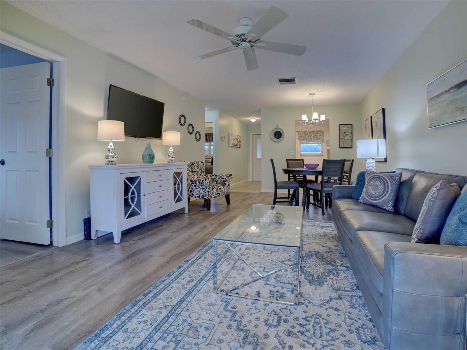 A living room features a grey sofa, glass coffee table, white console, and dining area — 400 SW Golfview Terrace # 111, Boynton Beach FL 33426, BOYNTON BEACH, FL